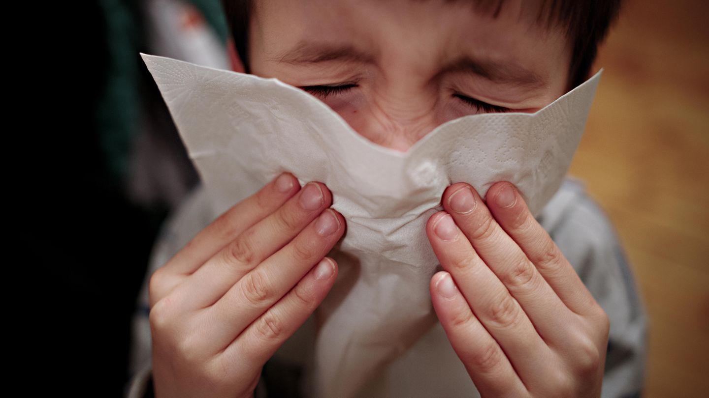 Ein Junge hält ein Taschentuch vor sein Gesicht