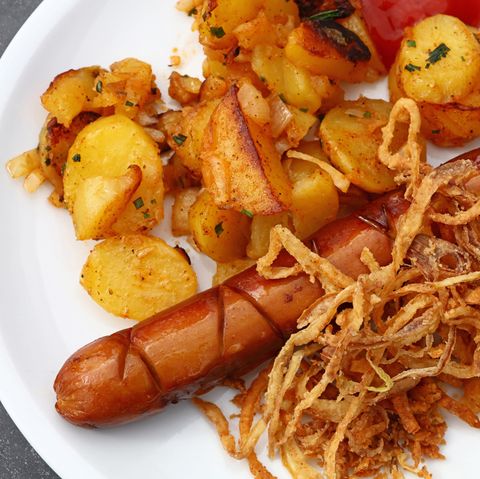 Auf einem Teller liegen Wurst und Bratkartoffeln