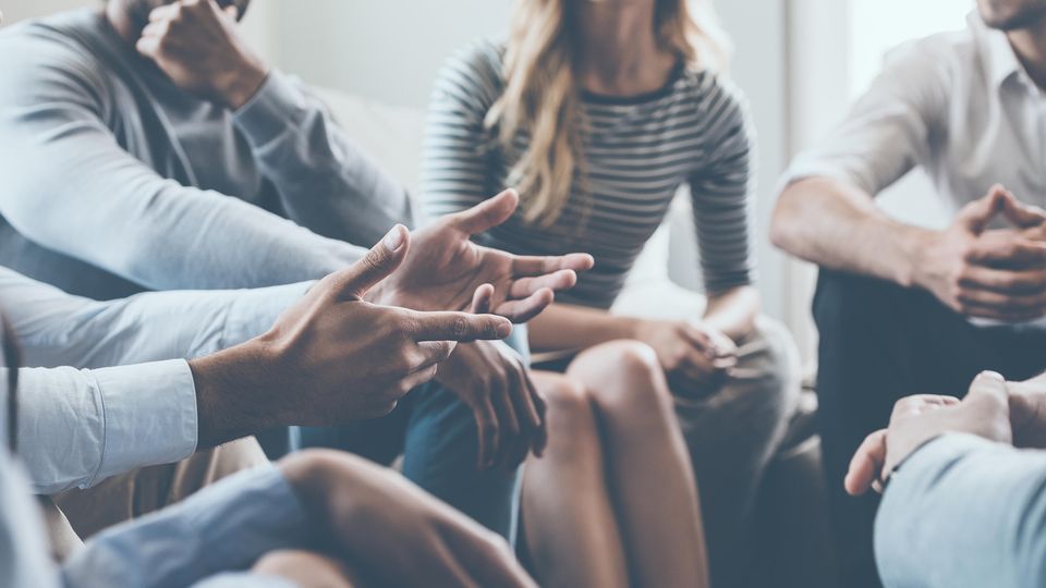 Einige Personen sitzen im Kreis im Rahmen einer Gruppentherapie zu Burn-out