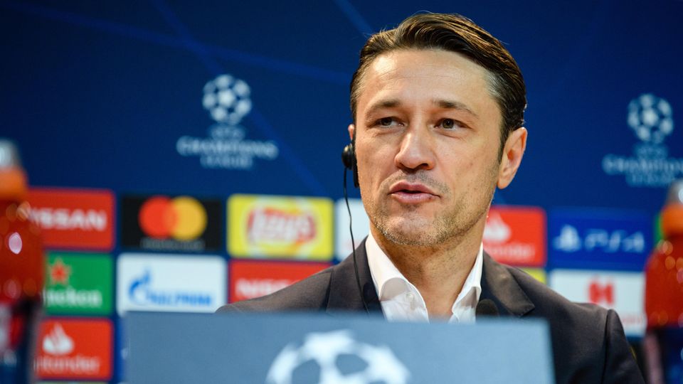 Niko Kovac sitzt auf einem Podium mit Champions-League-Loho und hört mit Knopf im Ohr einer Frage zu
