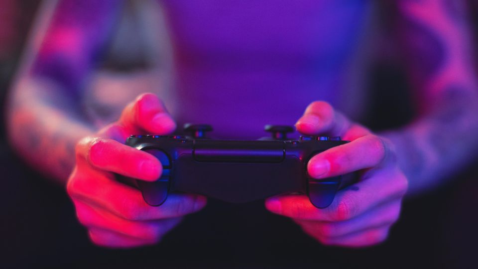 Ein Gamer hält eine Playstation-Konsole in den Händen