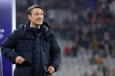 In dunkelblauer Winterjacke steht Niko Kovac am Spielfeldrand und grinst beim Blick auf den Spielstand