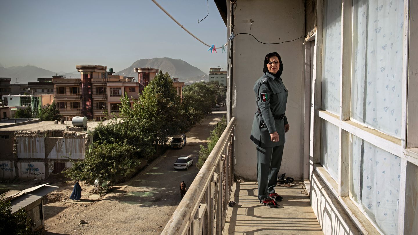 Schamila steht in Uniform auf dem Balkon ihrer Wohnung. Im Hintergrund kann man die Berge des Hindukuschs erkennen. Schamila wurde als Zwölfjährige entführt und von Afghanistan nach Pakistan verschleppt.