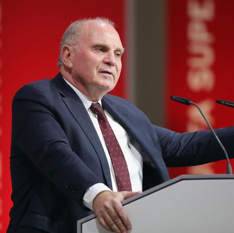 Uli Hoeneß steht vor einem großen Wappen des FC Bayern München