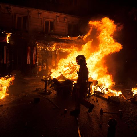 In Paris geht ein Polizist an einem brennenden Haufen Stühle vorbei. Rund um die Champs-Élysées kam es am Samstag zu heftigen Krawallen bei Demonstrationen der "Gelben Westen".