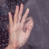 Frauen Hand an einer nassen Scheibe