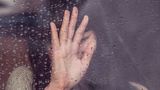 Frauen Hand an einer nassen Scheibe