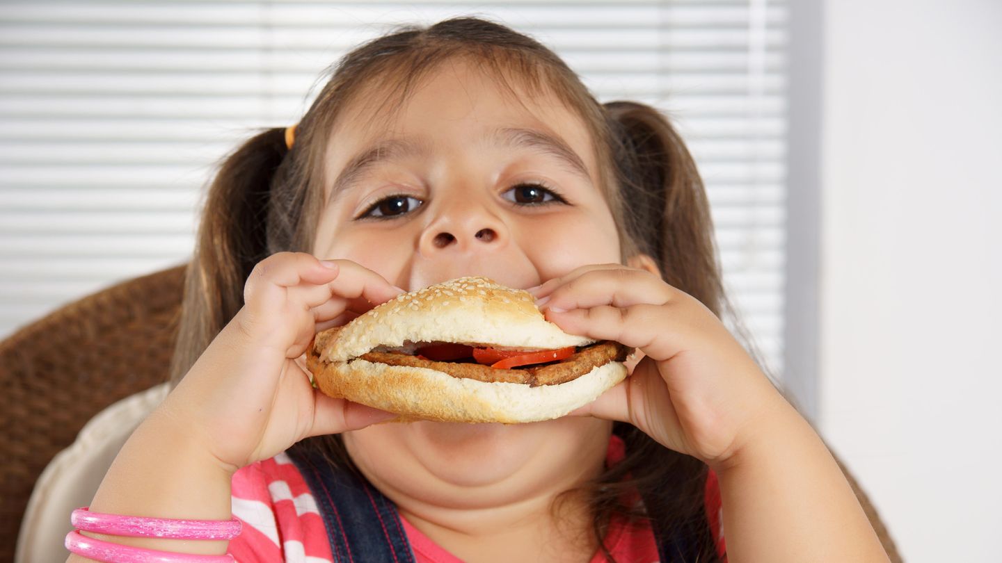 Ein übergewichtiges Mädchen beißt in einen Burger