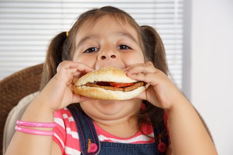 Ein übergewichtiges Mädchen beißt in einen Burger