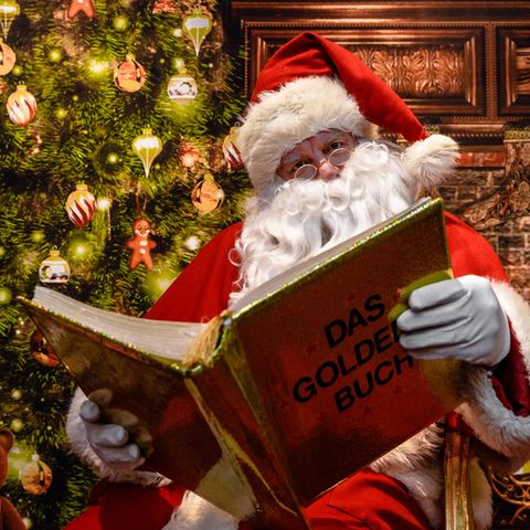 Ein Weihnachtsmann - hier ein Exemplar aus Schleswig-Holstein - liest aus einem goldenen Buch