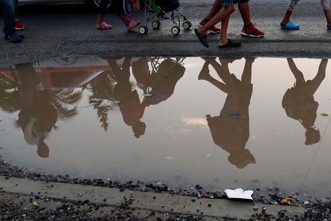 Migranten aus Mittelamerika spiegeln sich in einer Pfütze am Straßenrand. Sie sind Teil einer Gruppe tausender Menschen, die aus Mittelamerika vor der Gewalt durch Jugendbanden und der schlechten wirtschaftlichen Lage in der Region fliehen und sich auf dem Weg in die USA befinden.