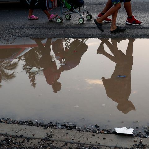 Migranten aus Mittelamerika spiegeln sich in einer Pfütze am Straßenrand. Sie sind Teil einer Gruppe tausender Menschen, die aus Mittelamerika vor der Gewalt durch Jugendbanden und der schlechten wirtschaftlichen Lage in der Region fliehen und sich auf dem Weg in die USA befinden.