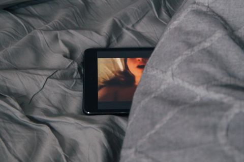 Handy mit Porno in einem Bett