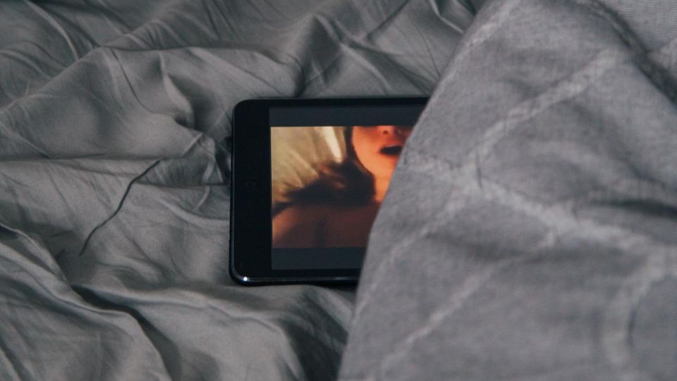 Handy mit Porno in einem Bett