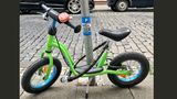 Wiesbaden, Deutschland. Man muss nur einfallsreich sein: Jemand hat das Laufrad eines Kindes an einen Laternenmast angekettet. An dem Mast wurde ein Aufkleber angebracht, der ein angekettetes hellgrünes Laufrad für Kleinkinder zeigt. Über dem Foto steht auf blauem Grund ein weißes P - darunter das Wort "only" - nur.  