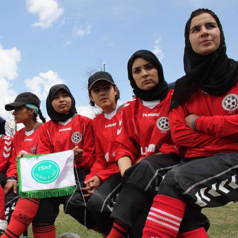 Die afghanische Frauenfußballmannschaft sitzt in einer Reihe.