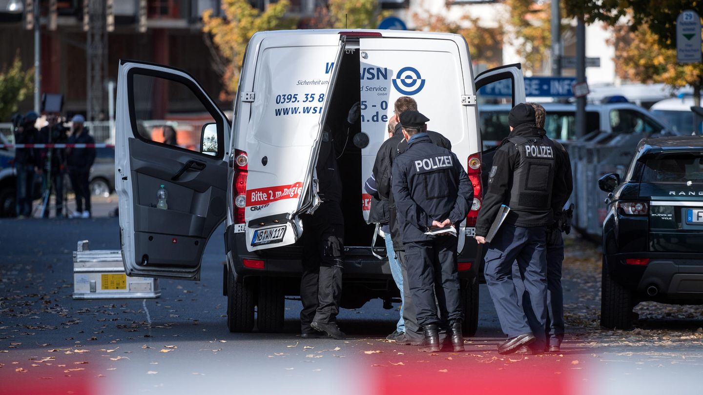 Polizeibeamte stehen an einem Geldtransporter mit aufgebrochenen Türen