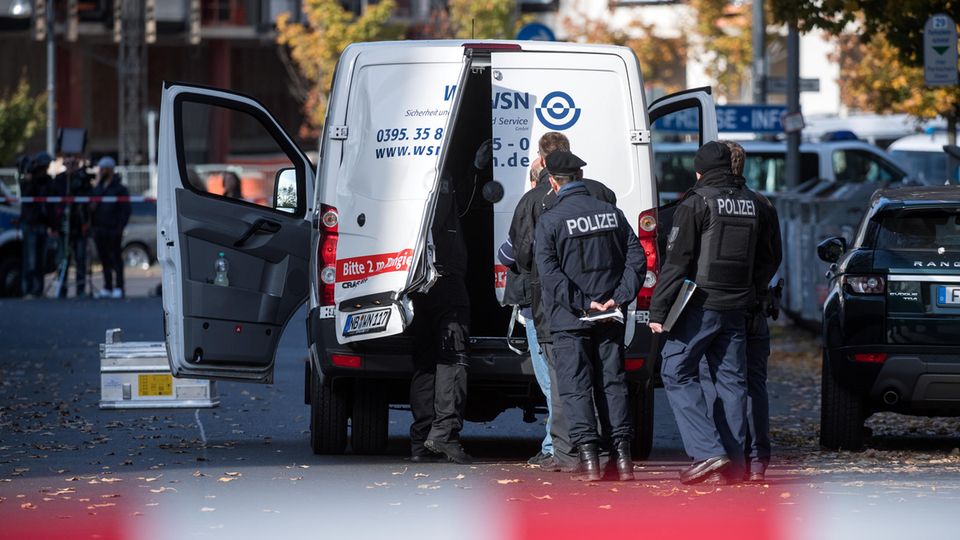 Polizeibeamte stehen an einem Geldtransporter mit aufgebrochenen Türen Polizeibeamte stehen an einem Geldtransporter mit aufgebrochenen Türen