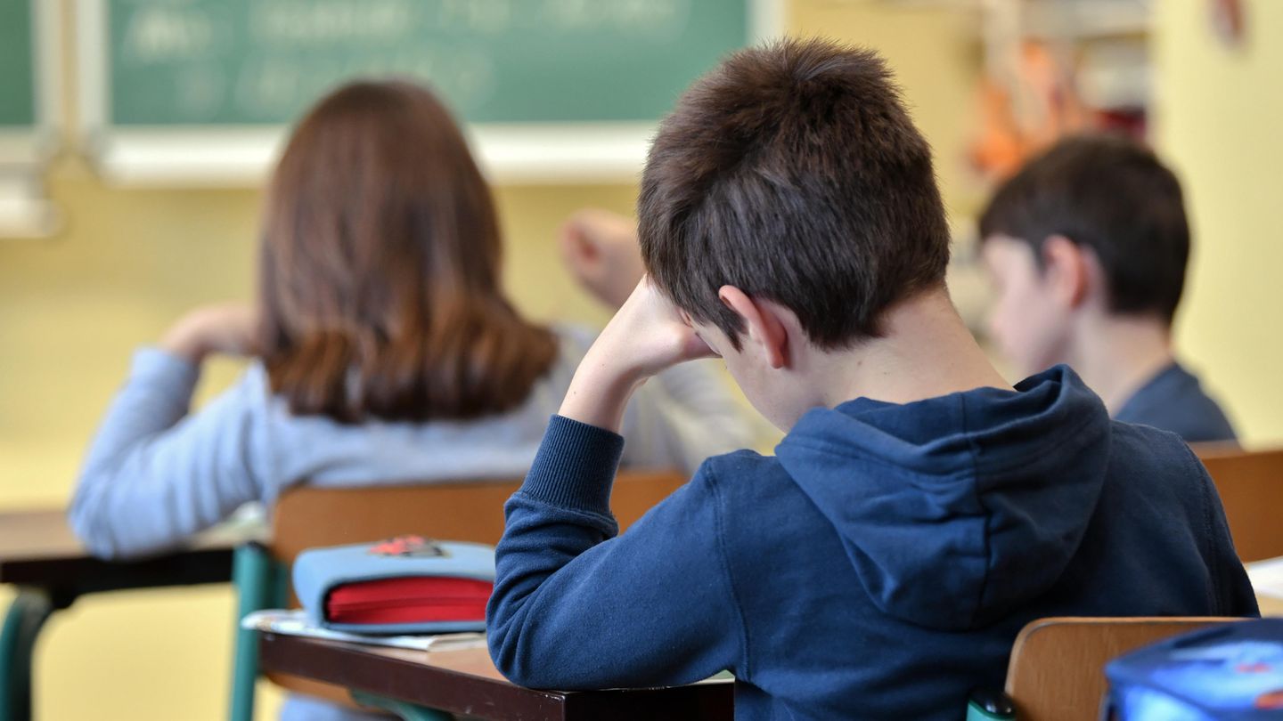 Schüler sitzt mit abgestützter Hand in Schulklasse