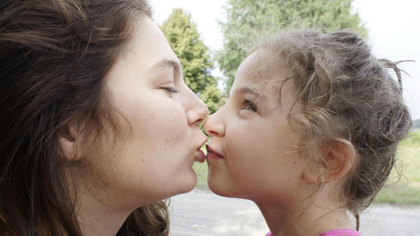 Eine Mutter will ihre kleine Tochter küssen