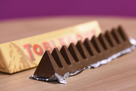 Ein dreieckiger Tobleroneriegel liegt ausgepackt neben der Verpackung
