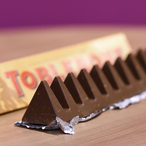 Ein dreieckiger Tobleroneriegel liegt ausgepackt neben der Verpackung