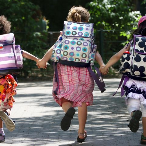 Drei Kinder mit Schulranzen rennen