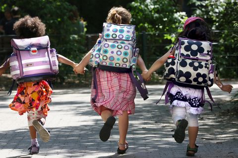 Drei Kinder mit Schulranzen rennen