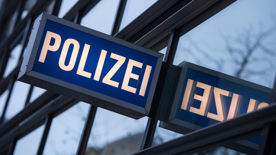 In den Scheiben einer Polizeiwache spiegelt sich ein "Polizei"-Leuchtschild
