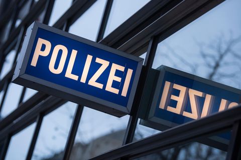 In den Scheiben einer Polizeiwache spiegelt sich ein "Polizei"-Leuchtschild