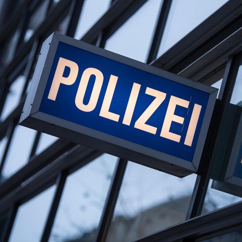In den Scheiben einer Polizeiwache spiegelt sich ein "Polizei"-Leuchtschild
