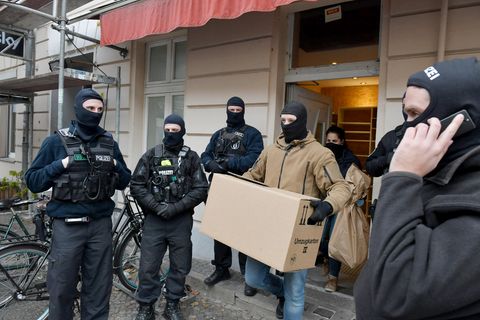 Vermummte Ermittler tragen unter Schutz des SEK Kartons und Tüten aus einer Moschee in Berlin-Wedding