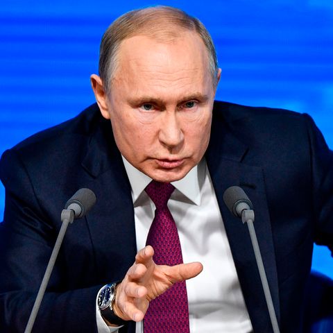 Russlands Präsident Wladimir Putin sitzt hinter zwei Mikros und vor einer blauen Wand während einer Pressekonferenz