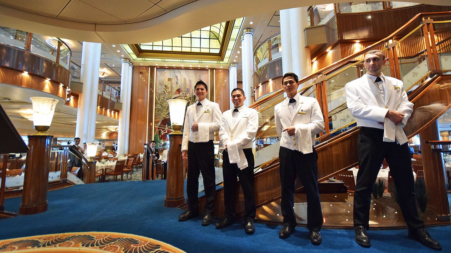 Hartes Arbeitspensum, wenig Lohn: Servicekräfte am Eingang zum Hauptrestaurant eines Kreuzfahrtschiffes