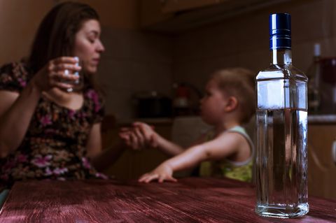 Ein Frau trinkt Alkohol im Beisein ihres kleinen Kindes