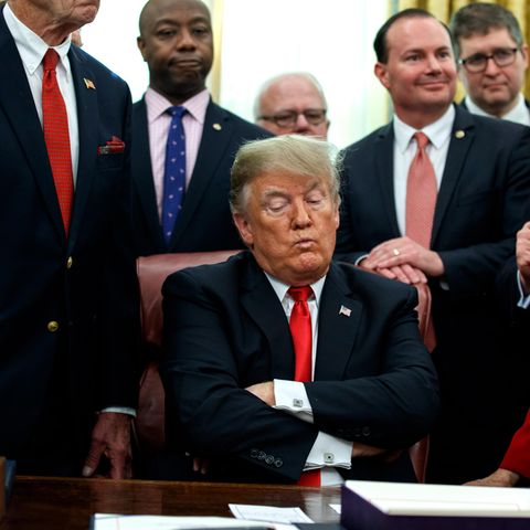 US-Präsident Donald Trump sitzt mit verschränkten Armen an einem Schreibtisch und schaut verkniffen