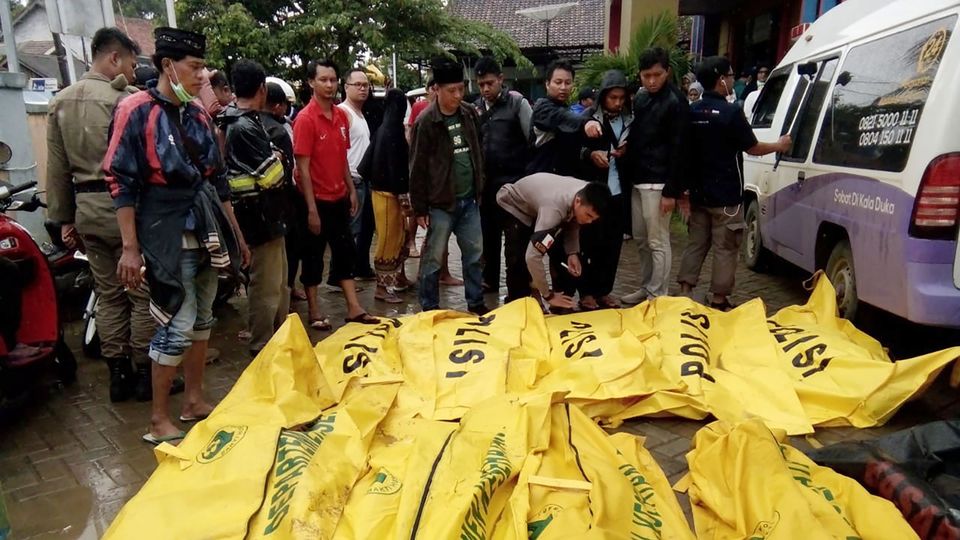 Tsunami Indonesien Todesopfer Eine Gruppe Männer steht vor etwa zwölf knallgelben Leichensäcken, in denen Todesopfer des Tsunamis liegen