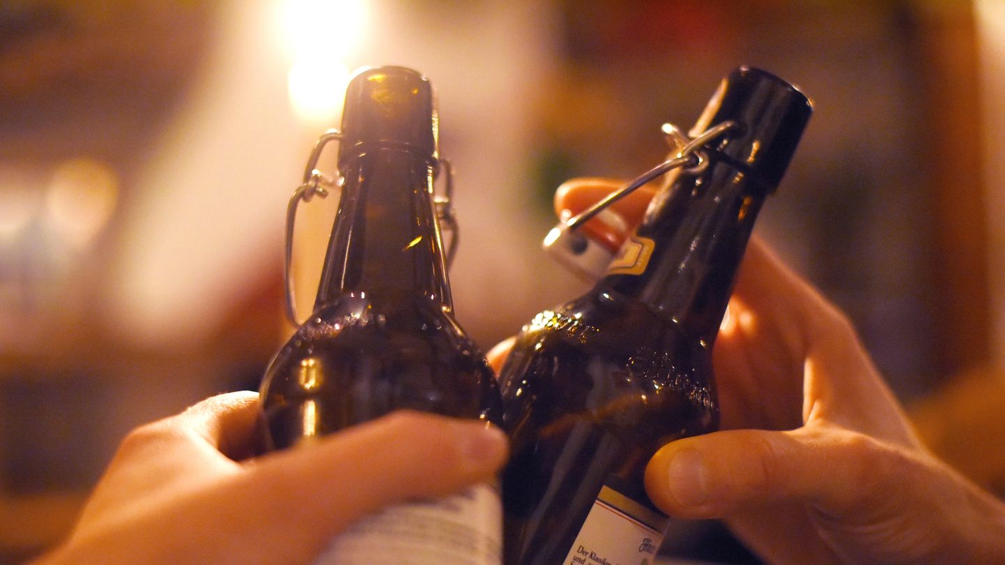 Zwei Hände stoßen mit zwei 0,5 Liter Bierflaschen an