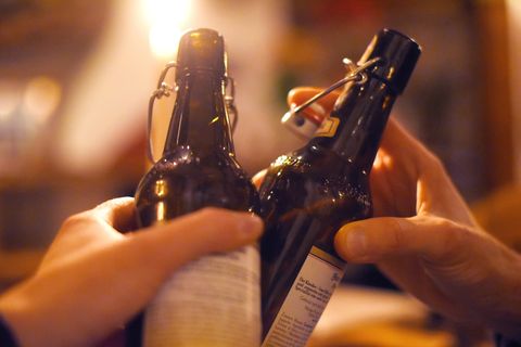 Zwei Hände stoßen mit zwei 0,5 Liter Bierflaschen an