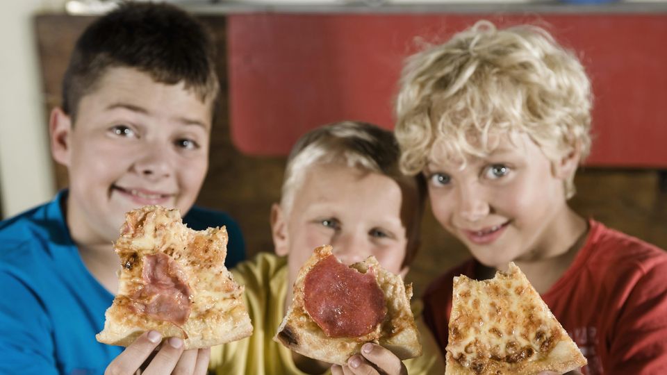 Drei Jungen mit Pizzastücken in der Hand