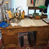 Ein Schreibtisch mit Kujaus Fälscherutensilien: Hinten links steht ein hoher Mixer zum Anrühren von Tinte, Rezeptur nach Gusto mit schwarzer und blauer Pelikan-Tinte (ebenfalls links auf dem Schreibtisch). Kujau musste immer andere Tintenfarben benutzen, damit die Tagebücher authentischer aussahen - als wären sie über Jahre hinweg geschrieben worden. Der Mixer stammt aus den 50er Jahren, er ist das einzige Modell, das vorne einen Ausguss hatte. Davor wurde ein Glas gestellt, in das die angemischte Tinte hineinlief und in das dann die Schreibfeder eingetaucht wurde. Kujau verwendete eine Stahlfeder in einem Federhalter.  Um die Tagebuchseiten alt aussehen zu lassen, hat Kujau das Papier mit schwarzem Tee vergilbt und dann mit dem Bügeleisen gebügelt, damit das Papier schön glatt ist.  Der Schreibtisch selbst gehörte nicht Kujau.