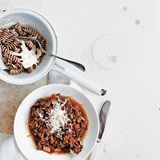 Pasta Bolognese  Zutaten:  Olivenölspray, 250 g mageres Rinderhackfleisch, 1 Zwiebel, gehackt, 1 Möhre, gehackt, 1 Knoblauchzehe, fein gehackt, 2 Dosen (à 400 g) gewürfelte Tomaten, Salz und frisch gemahlener schwarzer Pfeffer, 100 g grüne Linsen, 80 g Vollkornpasta, 1 Tomate, in Spalten geschnitten, 1 Esslöffel Olivenöl, frisch gepresster Saft von ½ Zitrone, 2 Esslöffel frisch geriebener Parmesan, 80 g Knollensellerie, geschält und gerieben      Zubereitung:  Eine tiefe Pfanne mit etwas Olivenöl einsprühen und bei mittlerer bis hoher Hitze erwärmen. Rinderhackfleisch, Zwiebel, Möhre sowie Knoblauch zugeben und 6 –8 Minuten garen, bis das Fleisch gebräunt ist; dabei häufig umrühren. Tomaten und Saft (aus der Dose) zugeben und aufkochen. Die Hitze stark reduzieren und die Sauce ohne Deckel 20 Minuten oder länger kochen, bis sie eindickt; mit etwas Salz und Pfeffer würzen.      In der Zwischenzeit Wasser in einem Topf bei mittlerer bis hoher Hitze zum Kochen bringen. Die Linsen darin 12–14 Minuten kochen, bis sie gerade weich sind; mit etwas Salz und Pfeffer würzen.      In einem zweiten Topf Salzwasser bei hoher Hitze zum Kochen bringen. Die Pasta in das Wasser geben und nach Packungsanweisung al dente kochen; dann abgießen und kurz abbrausen.      Linsen, Tomate, Olivenöl und Zitronensaft mit 1 Prise Salz in einer kleinen Schüssel verrühren.      Die Fleischsauce über die Pasta geben, Parmesan sowie Knollensellerie darüberstreuen und mit dem Linsensalat als Beilage servieren. Alternativ die Linsenmischung in die Fleischsauce rühren.