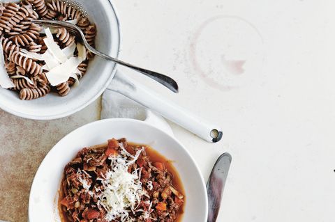 Pasta Bolognese  Zutaten:  Olivenölspray, 250 g mageres Rinderhackfleisch, 1 Zwiebel, gehackt, 1 Möhre, gehackt, 1 Knoblauchzehe, fein gehackt, 2 Dosen (à 400 g) gewürfelte Tomaten, Salz und frisch gemahlener schwarzer Pfeffer, 100 g grüne Linsen, 80 g Vollkornpasta, 1 Tomate, in Spalten geschnitten, 1 Esslöffel Olivenöl, frisch gepresster Saft von ½ Zitrone, 2 Esslöffel frisch geriebener Parmesan, 80 g Knollensellerie, geschält und gerieben      Zubereitung:  Eine tiefe Pfanne mit etwas Olivenöl einsprühen und bei mittlerer bis hoher Hitze erwärmen. Rinderhackfleisch, Zwiebel, Möhre sowie Knoblauch zugeben und 6 –8 Minuten garen, bis das Fleisch gebräunt ist; dabei häufig umrühren. Tomaten und Saft (aus der Dose) zugeben und aufkochen. Die Hitze stark reduzieren und die Sauce ohne Deckel 20 Minuten oder länger kochen, bis sie eindickt; mit etwas Salz und Pfeffer würzen.      In der Zwischenzeit Wasser in einem Topf bei mittlerer bis hoher Hitze zum Kochen bringen. Die Linsen darin 12–14 Minuten kochen, bis sie gerade weich sind; mit etwas Salz und Pfeffer würzen.      In einem zweiten Topf Salzwasser bei hoher Hitze zum Kochen bringen. Die Pasta in das Wasser geben und nach Packungsanweisung al dente kochen; dann abgießen und kurz abbrausen.      Linsen, Tomate, Olivenöl und Zitronensaft mit 1 Prise Salz in einer kleinen Schüssel verrühren.      Die Fleischsauce über die Pasta geben, Parmesan sowie Knollensellerie darüberstreuen und mit dem Linsensalat als Beilage servieren. Alternativ die Linsenmischung in die Fleischsauce rühren.