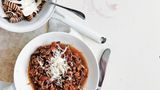 Pasta Bolognese  Zutaten:  Olivenölspray, 250 g mageres Rinderhackfleisch, 1 Zwiebel, gehackt, 1 Möhre, gehackt, 1 Knoblauchzehe, fein gehackt, 2 Dosen (à 400 g) gewürfelte Tomaten, Salz und frisch gemahlener schwarzer Pfeffer, 100 g grüne Linsen, 80 g Vollkornpasta, 1 Tomate, in Spalten geschnitten, 1 Esslöffel Olivenöl, frisch gepresster Saft von ½ Zitrone, 2 Esslöffel frisch geriebener Parmesan, 80 g Knollensellerie, geschält und gerieben      Zubereitung:  Eine tiefe Pfanne mit etwas Olivenöl einsprühen und bei mittlerer bis hoher Hitze erwärmen. Rinderhackfleisch, Zwiebel, Möhre sowie Knoblauch zugeben und 6 –8 Minuten garen, bis das Fleisch gebräunt ist; dabei häufig umrühren. Tomaten und Saft (aus der Dose) zugeben und aufkochen. Die Hitze stark reduzieren und die Sauce ohne Deckel 20 Minuten oder länger kochen, bis sie eindickt; mit etwas Salz und Pfeffer würzen.      In der Zwischenzeit Wasser in einem Topf bei mittlerer bis hoher Hitze zum Kochen bringen. Die Linsen darin 12–14 Minuten kochen, bis sie gerade weich sind; mit etwas Salz und Pfeffer würzen.      In einem zweiten Topf Salzwasser bei hoher Hitze zum Kochen bringen. Die Pasta in das Wasser geben und nach Packungsanweisung al dente kochen; dann abgießen und kurz abbrausen.      Linsen, Tomate, Olivenöl und Zitronensaft mit 1 Prise Salz in einer kleinen Schüssel verrühren.      Die Fleischsauce über die Pasta geben, Parmesan sowie Knollensellerie darüberstreuen und mit dem Linsensalat als Beilage servieren. Alternativ die Linsenmischung in die Fleischsauce rühren.