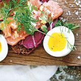 Offenes Sandwich mit Lachs, Ingwer & Limette      Zutaten:  120 g Lachsfilet in Sushi-Qualität, dünn quer zur Fleischfaser geschnitten Salz und frisch gemahlener schwarzer Pfeffer 1 Teelöffel fein gehackter frischer Ingwer abgeriebene Schale und frisch gepresster Saft von 1 Bio-Limette 1 Scheibe Roggenvollkornbrot oder Pumpernickel, getoastet 3 bittere Salatblätter, z. B. Radicchio 1 Ei (Größe L), hart gekocht und halbiert frische Dillspitzen zum Servieren      Zubereitung:  Den Lachs auf einen Teller legen, mit etwas Salz und Pfeffer würzen. Den Fisch mit Ingwer und Limettenschale bestreuen, mit Limettensaft beträufeln.