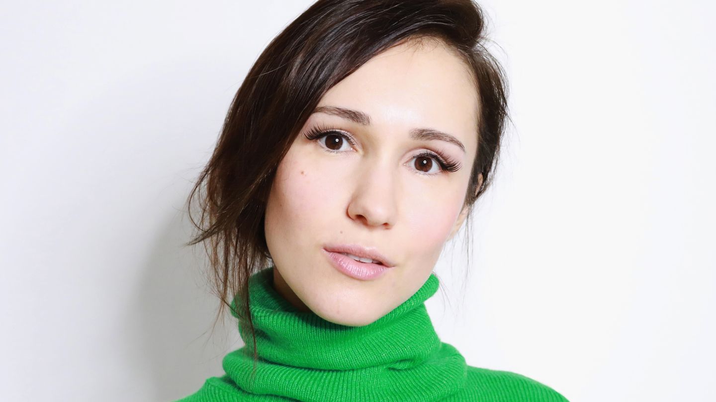 Eine junge Frau in einem knallgrünen Rollkragenpullover