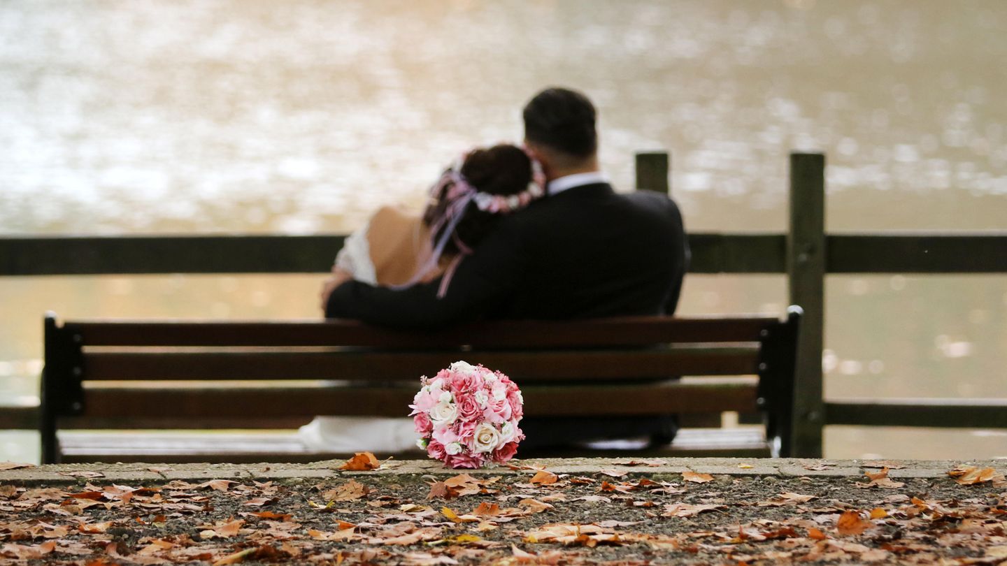 Ein Hochzeitspaar sitzt auf einer Bank
