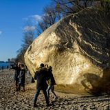 Hamburg, Deutschland. Die Sonne scheint auf den Findling „Der alte Schwede“ am Ufer der Elbe. 1999 wurde der 217 Tonnen schwere Koloss bei der Vertiefung der Fahrrinne in ca. 15 Meter Tiefe gefunden und ist für viele Hamburger und Touristen eine Attraktion. Unbekannte haben den großen Stein jetzt mit Goldfarbe angemalt.