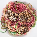 Zoodles in Rote-Bete-Pesto mit Hähnchennuggets      Zutaten:  Für das Rote-Bete-Pesto: 2 kleine frische Knollen Rote Bete (à ca. 75 g), Salz, 10 g Pinienkerne, 1 Knoblauchzehe, 15 g Parmesan, ½ unbehandelte Orange, 1–2 EL Olivenöl, frisch gemahlener schwarzer Pfeffer  Für die Zoodles: 1 große Zucchini, 100 g Dinkel-Spaghetti, Salz  Für die Hähnchennuggets: 1 Hähnchenfilet (ca. 150 g), Salz, frisch gemahlener schwarzer Pfeffer, 1 kleines Ei (Größe S), 1 EL Dinkelmehl Type 1050, 1 Scheibe Pumpernickel (ca. 42 g), 1 TL Sesamsamen, 1 EL Olivenöl zum Braten      Zubereitung:  Für das Rote-Bete-Pesto die Rote Bete in kochendem Salzwasser in etwa  50 Minuten weich garen. Abgießen, etwas abkühlen lassen und grob würfeln.  Die Pinienkerne in einer kleinen beschichteten Pfanne ohne Fett  goldgelb anrösten, herausnehmen und auskühlen lassen. Den Knoblauch  abziehen und grob hacken. Den Parmesan ebenfalls grob hacken.  Die Orange fein abreiben, 4–5 EL Saft auspressen, beides mit der Roten  Bete, den Pinienkernen, dem Knoblauch, dem Parmesan und dem Olivenöl  in einen hohen Rührbecher geben und mit dem Mixstab fein pürieren. Das  Pesto mit dem Salz und dem Pfeffer abschmecken.  Für die Zoodles die Zucchini waschen und mit einem Spiralschneider zu  Zucchini-Spaghetti schneiden. Die Dinkel-Spaghetti in reichlich kochendem  Salzwasser bissfest garen. Etwa 2 Minuten vor Ende der Garzeit Zucchini-  Spaghetti zugeben und mitgaren.  Für die Hähnchennuggets das Hähnchenfilet waschen, trockentupfen,  in große Würfel schneiden und mit Salz und Pfeffer würzen. Das Ei in  einem tiefen Teller mit einer Gabel verquirlen. Das Dinkelmehl auf einem  flachen Teller verteilen. Das Pumpernickel grob zerbröseln und dann im  Blitzhacker feiner mahlen. Die Brösel mit dem Sesam mischen und auf  einem flachen Teller verteilen. Die Hähnchenwürfel zuerst in dem Mehl  wenden, dann durch das Ei ziehen und zuletzt mit der Pumpernickel-  Sesam-Mischung panieren.  Das Olivenöl in einer Pfanne erhitzen und die Hähnchenwürfel bei mittlerer  Temperatur von beiden Seiten knusprig braten. Die Zoodles abgießen,  mit dem Pesto mischen, auf Pastatellern anrichten, die Hähnchennuggets  daraufsetzen und servieren.      Mehr Rezepte finden Sie in in: Sporternährung für jeden Tag, 240 Seiten, 29,99 Euro