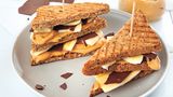 Chocolover’s Erdnussbutter- Banana-Sandwich      Zutaten:  Für die Erdnussbutter: 150 g geröstete, ungesalzene Erdnusskerne, 20 g Vollrohrzucker, 1 TL Kokosöl, 1 Msp. Vanilleextrakt, 1 Prise feines Meersalz  Für die Schokotäfelchen: 75 g Zartbitterschokolade (mind. 70 %)  Für das Sandwich: 1 kleine Banane 8 Scheiben Vollkornsandwichbrot  Außerdem: Back- oder Pergamentpapier      Zubereitung:  Die Erdnüsse in eine Küchenmaschine oder einen Standmixer geben und 2–3 Minuten mixen bis eine glatte, cremige Masse entstanden ist. Den Vollrohrzucker, das Kokosöl, den Vanilleextrakt und das Salz zufügen und nochmals etwa 1 Minute mixen, bis sich alle Komponenten gut verbunden haben. Die Schokolade grob hacken und über einem heißen Wasserbad vorsichtig schmelzen. Ein glattes Stück Back- oder Pergamentpapier auf einem großen Brett auslegen, die Schokolade darauf gießen und mit einem Löffel oder einer Winkelpalette glatt und dünn verstreichen. Das Brett für etwa 15 Minuten in den Kühlschrank stellen. Die Schokolade mit einem Pizzaschneider oder scharfen Messer in Rechtecke schneiden. Falls noch einige Stellen der Schokolade zu weich sind, nochmals in den Kühlschrank stellen und dann den Rest in Rechtecke schneiden. Die Banane schälen und in dünne Scheiben schneiden. Die Brotscheiben rösten und die Hälfte der Brotscheiben mit Erdnussbutter bestreichen. Die Bananenscheiben und Schokotäfelchen auf den Brotscheiben verteilen, mit den übrigen Brotscheiben abdecken, diagonal halbieren und servieren.      Mehr Rezepte finden Sie in in: Sporternährung für jeden Tag, 240 Seiten, 29,99 Euro